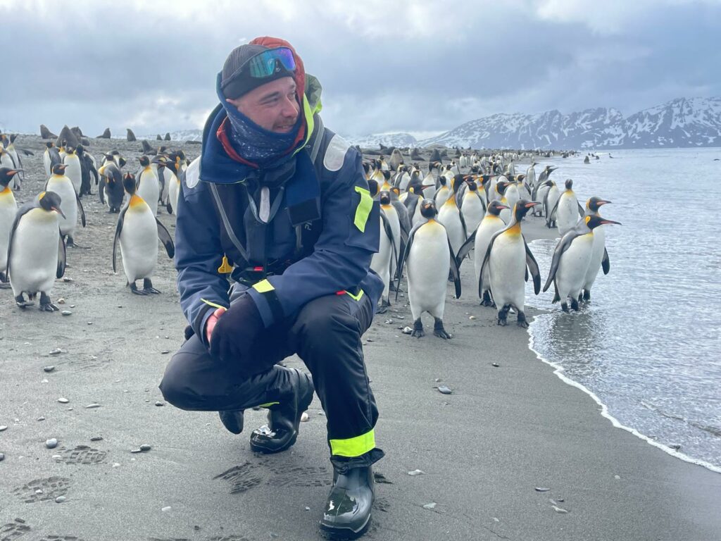 Maxime Potier au milieu d’un groupe de manchots en Antarctique